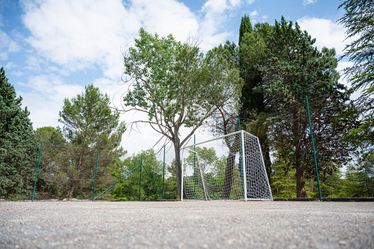 Voetbaldoel op een sportveld omringd door hoge bomen en hekwerk bij Camping Pian Di Boccio, Umbrië, Italië.