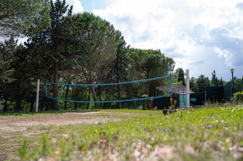 Campo da pallavolo all’aperto con rete su prato erboso, circondato da alberi al Camping Pian Di Boccio, Umbria.