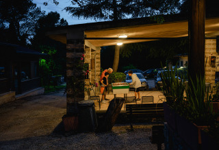 Due persone giocano a calcio balilla la sera sotto una terrazza coperta al Camping Pian Di Boccio, Umbria, Italia.