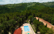 Vista dall'alto del Camping Pian Di Boccio in Umbria, Italia, con piscina e colline verdi circostanti.