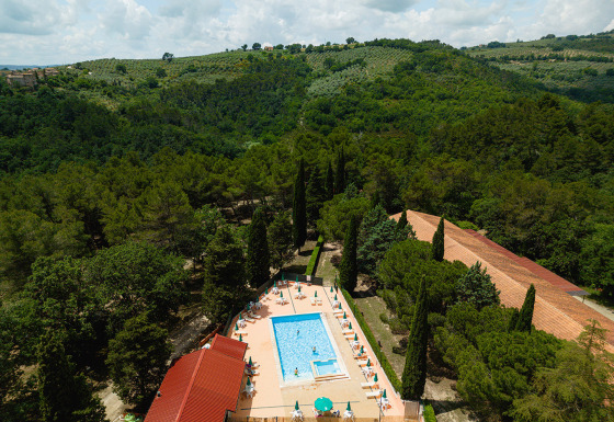 Vista dall'alto del Camping Pian Di Boccio in Umbria, Italia, con piscina e colline verdi circostanti.