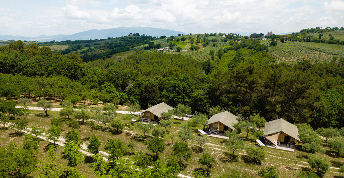 Luchtfoto van Camping Pian Di Boccio in Umbrië, Italië, met safaritenten tussen bomen en glooiende heuvels.