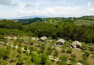 Vista aerea di Camping Pian Di Boccio in Umbria, Italia, con tende glamping tra alberi e dolci colline verdi.