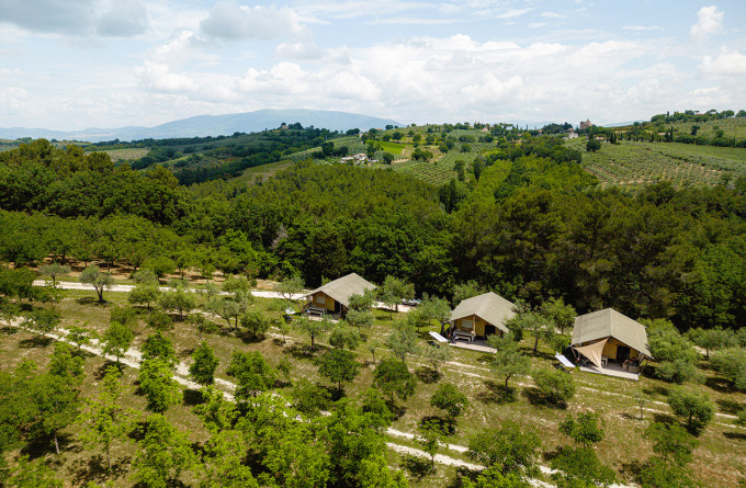Luchtfoto van Camping Pian Di Boccio in Umbrië, Italië, met safaritenten tussen bomen en glooiende heuvels.