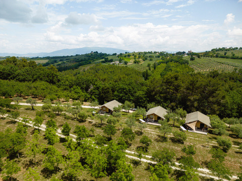 Aerial view of Camping Pian Di Boccio holiday park in Umbria, Italy, with glamping tents among trees and hills.