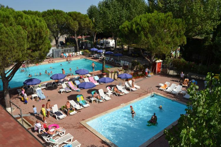 Gäste entspannen an Pools mit Liegestühlen und Sonnenschirmen im Camping Punta Navaccia, Umbrien, Italien.