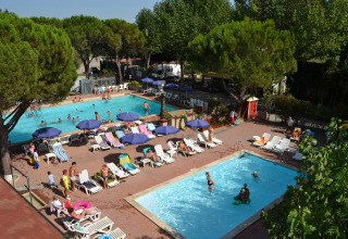 Familier nyder swimmingpools og afslapning blandt solsenge og parasoller i Camping Punta Navaccia, Umbrien.