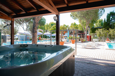 Vasca idromassaggio e piscina all’aperto tra alberi al Camping Punta Navaccia, villaggio in Umbria, Italia.