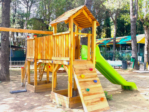 Un parco giochi con casetta in legno, scivolo e altalene al Camping Punta Navaccia in Umbria, Italia.