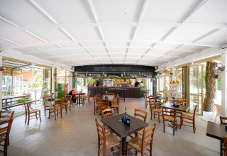 Lichte, ruime cafetaria met houten stoelen en tafels in Camping Punta Navaccia, Umbrië, Italië.