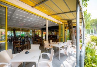 Buitenterras met witte en houten stoelen bij Camping Punta Navaccia vakantiepark in Umbrië, Italië.
