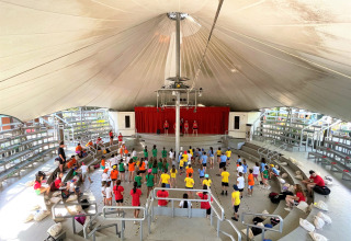 Kinderen nemen deel aan een activiteit in het overdekte amfitheater van Camping Punta Navaccia in Umbrië.