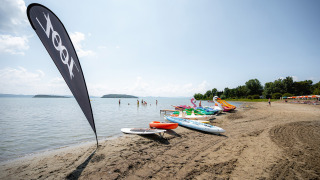 Playa en Camping Punta Navaccia, Umbría, Italia, con hidropedales y tablas de paddle surf en un día soleado.