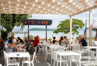 Area ristorante all'aperto con vista lago al Camping Punta Navaccia, villaggio turistico in Umbria, Italia.