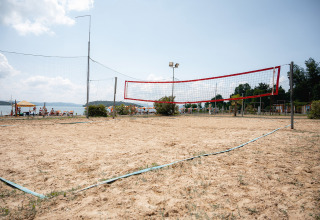 Campo da beach volley sabbioso al Camping Punta Navaccia in Umbria, Italia, con vista sul lago e persone rilassate.