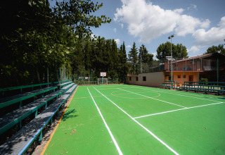 Outdoor green basketball court with bleachers at Camping Punta Navaccia holiday park in Umbria, Italy.