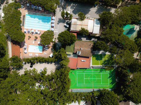 Vista aerea di Camping Punta Navaccia in Umbria, Italia, con piscine, campi sportivi e alberi.