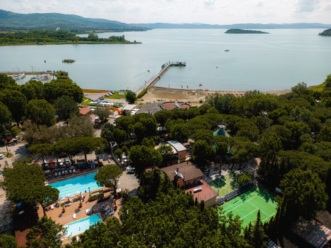 Luftfoto af Camping Punta Navaccia i Umbrien, Italien, med pool, sportplads, strand og søudsigt.