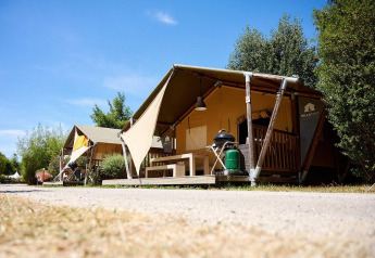 Tienda safari Villatent Nomad en Camping La Roche d’Ully, Francia, con vegetación y cielo azul claro.