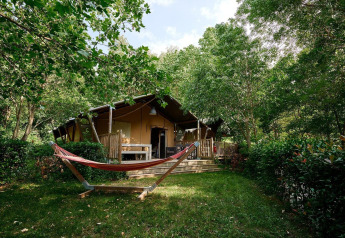 Tienda safari Villatent Nomad en Camping Le Canigou, Francia, rodeada de vegetación y una hamaca.