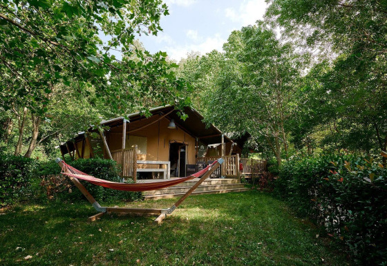 Tienda safari Villatent Nomad en Camping Le Canigou, Francia, rodeada de vegetación y una hamaca.