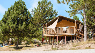 Lodge Villatent Nomad en Camping La Presqu’île, Francia, elevado y rodeado de pinos verdes.