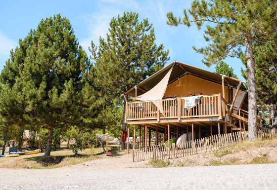 Lodge Villatent Nomad en Camping La Presqu’île, Francia, elevado y rodeado de pinos verdes.