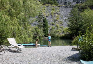 Zwei Kinder spielen am Ufer eines Flusses mit Liegestühlen bei Camping River in Provence-Alpes-Côte d’Azur, Frankreich.