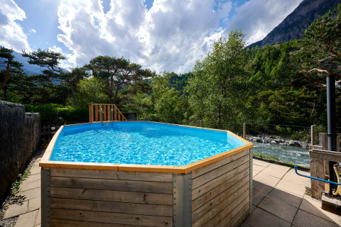 Piscina exterior con marco de madera en Camping River, rodeada de montañas y río en Provence-Alpes-Côte d’Azur.