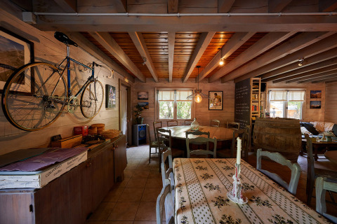 Cozy room with bicycle on wall, wooden beams, rustic tables and chairs at a Provence holiday park.