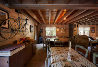 Knusse ruimte met fiets aan muur, houten balken en rustieke meubels in vakantiepark in de Provence.