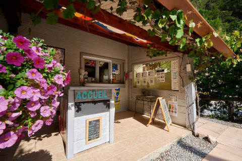 Recepción del Camping River en Provence-Alpes-Côte d’Azur, Francia, con flores y carteles informativos.
