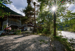 Buitenzicht bij Camping River in Provence-Alpes-Côte d’Azur met rivier, zon, bomen en gasten op het terras.