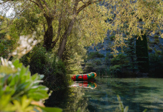 Kleurrijke opblaasboot op een kalme rivier tussen groene bomen in Provence-Alpes-Côte d’Azur, Frankrijk.