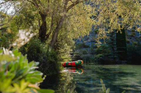 Kleurrijke opblaasboot drijft op een rustige rivier omgeven door bomen in Provence-Alpes-Côte d’Azur, Frankrijk.