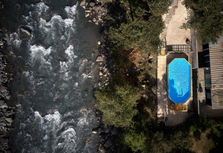 Vista aerea di una piscina accanto a un fiume, circondata da alberi, al Camping River, Provenza-Alpi-Costa Azzurra, Francia.