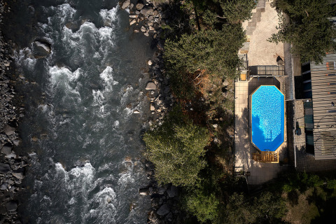 Vista aerea di una piscina accanto a un fiume, circondata da alberi, al Camping River, Provenza-Alpi-Costa Azzurra, Francia.