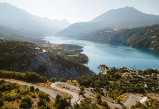Panoramabillede af Camping River feriestedet i Provence-Alpes-Côte d’Azur, Frankrig, med sø og bjerge.