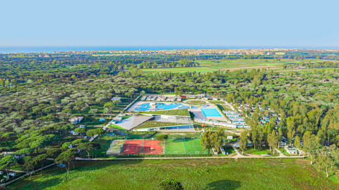 Vista aérea del Camping Roma Capitol en Lacio, Italia, con piscinas y canchas deportivas rodeadas de naturaleza.