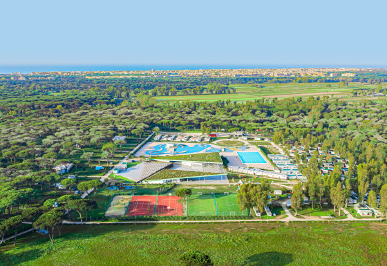 Vista aérea del Camping Roma Capitol en Lacio, Italia, con piscinas y canchas deportivas rodeadas de naturaleza.
