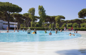Folk nyder en solrig dag ved den udendørs swimmingpool på Camping Roma Capitol i Lazio, Italien.
