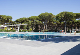 Piscina al Camping Roma Capitol, parco vacanze nel Lazio, Italia, circondata da alberi e visitatori.