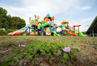 Colorido parque infantil con toboganes y torres en Camping Roma Capitol en Lacio, Italia, visto a nivel del suelo.