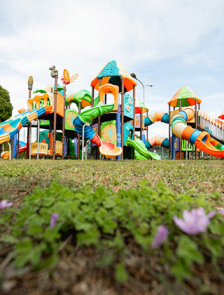 Colorido parque infantil con toboganes y torres en Camping Roma Capitol en Lacio, Italia, visto a nivel del suelo.