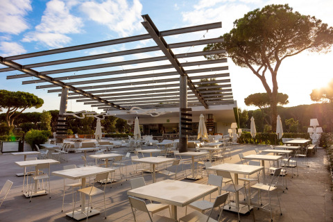 Zona pranzo all'aperto con tavoli e sedie moderne al Camping Roma Capitol, villaggio vacanze nel Lazio.