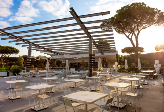 Outdoor dining area with modern tables and chairs at Camping Roma Capitol holiday park in Lazio, Italy.