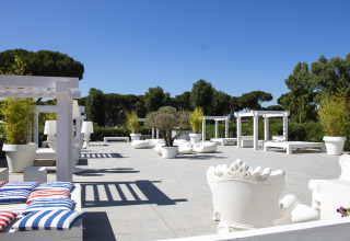 Buitenlounge met witte tuinmeubels en pergola’s bij Camping Roma Capitol in Lazio, Italië.