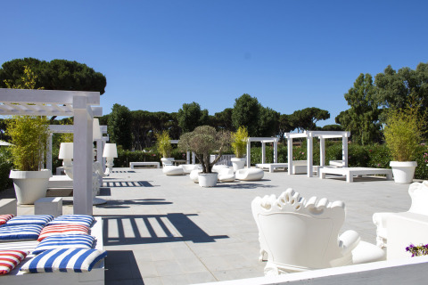Buitenlounge met witte tuinmeubels en pergola’s bij Camping Roma Capitol, Lazio, Italië.