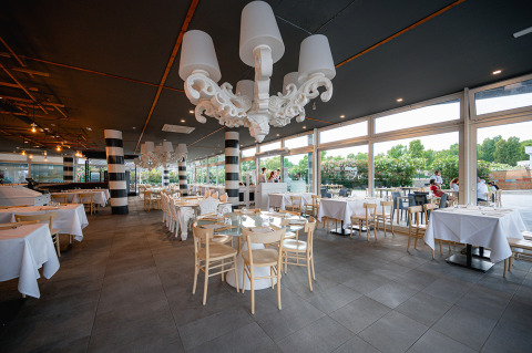 Restaurante moderno y luminoso con ventanas grandes y manteles blancos en Camping Roma Capitol, Lacio, Italia.