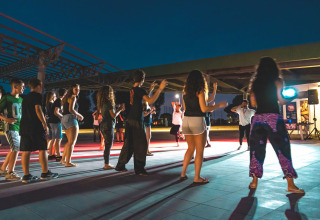 Giovani partecipano a una sessione di danza di gruppo all'aperto di sera al Camping Roma Capitol nel Lazio, Italia.